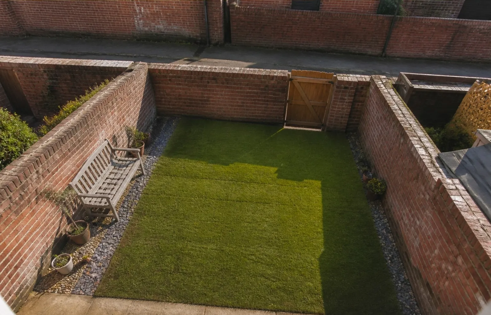 Walled back yard of a Tyneside terrace seen from above, with a new rectangle of turf and a bench